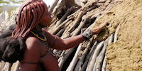 femme himba appliquant un torchi sur sa hutte - voyage exploration en namibie